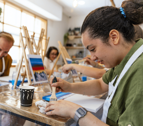 A lady painting watercolours in an art class.